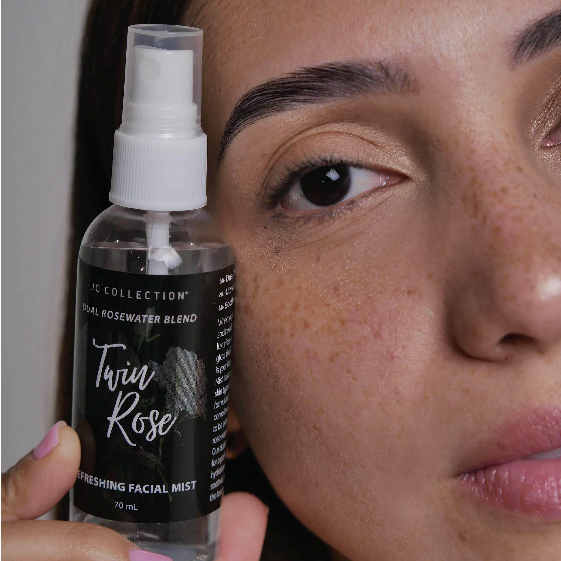 A woman holding by her face the Twin Rose facial mist